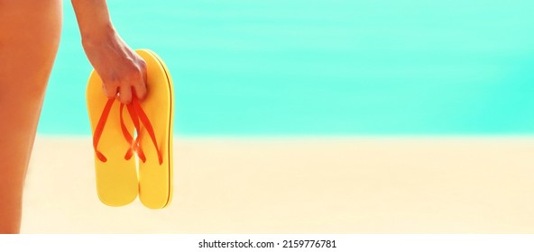 Close up woman holding flip flops on beach over sea background, summer vacation concept, banner blank copy space for advertising text