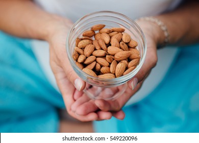 Close Up Of Woman Holding glass bowl with Almonds nuts. Healthy Organic Food.