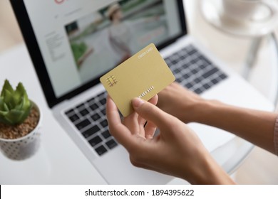 Close up woman holding golden plastic credit card mockup with number, paying online, girl using laptop, shopping online, doing internet secure payment, ordering and buying, ecommerce concept