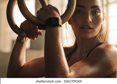 Close up of woman holding gymnastic rings at the gym and looking at camera. Fitness woman looking tired after intense  workout. - Powered by Shutterstock