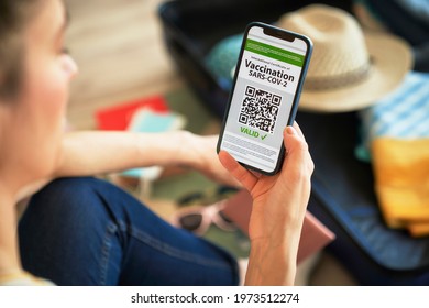 Close up of woman holding mobile phone with digital vaccination card                                - Powered by Shutterstock