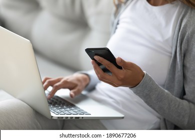 Close up woman holding phone, using laptop, shopping or chatting online, sitting on couch, young female freelancer or blogger working on project, student studying, engaged in internet course