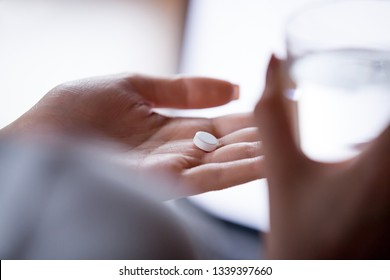 Close up woman holding pill in hand with water. Female going to take tablet from headache, painkiller, medication drinking clear water from glass. Healthcare, medicine, treatment, therapy concept - Shutterstock ID 1339397660