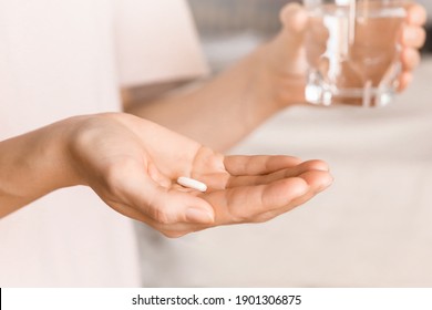 Close up woman holding pill in hand with water. Woman takes medicines with glass of water. Daily norm of vitamins, effective drugs, modern pharmacy for body and mental health concept.