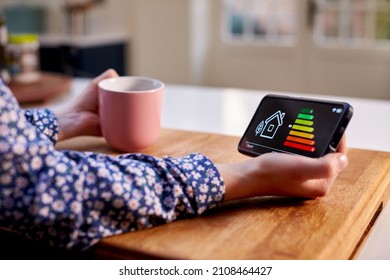 Close Up Of Woman Holding Smart Energy Meter In Kitchen Measuring Energy Efficiency - Shutterstock ID 2108464427