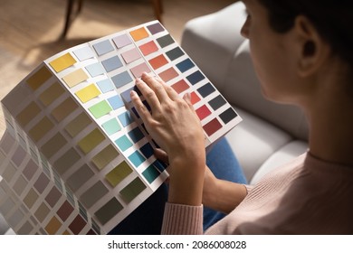 Close up woman homeowner choosing color from samples catalogue, preparing for house renovation concept, young female holding palette of wall paint colors, interior designer working on project