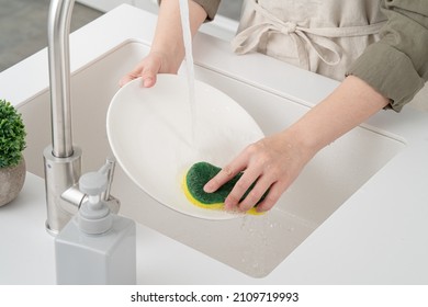 Close up of woman housewife is doing the dishes at home kitchen by using wash sponge and dishwashing. - Shutterstock ID 2109719993