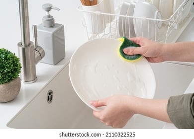 Close up of woman housewife is doing the dishes at home kitchen by using wash sponge and dishwashing. - Powered by Shutterstock