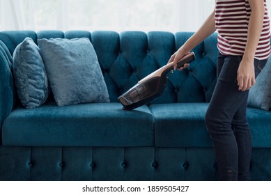 Close Up Of A Woman Housewife Vacuuming Furniture In A House With A Hand-held Portable Vacuum Cleaner