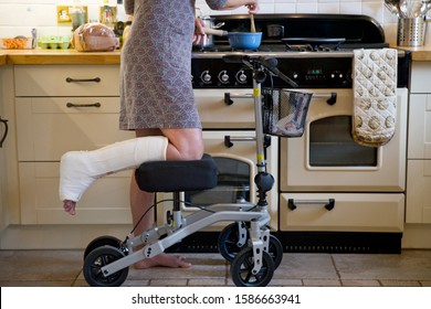 Close Up Of Woman With Leg In Plaster Cast At Home Using Mobility Aid Whilst Cooking Meal