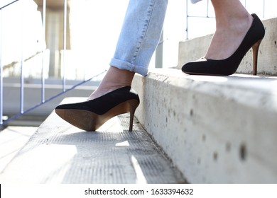 Close up of a woman legs with heels walking down stairs and spraining ankle
