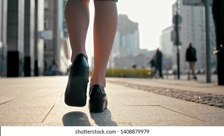 Close Up Woman Legs in Patent Platform Shoes Walking in the Center of Big City with Blurred Pedestrians and People Riding Bike and Scooter in Spring Sunny Day - Shutterstock ID 1408879979