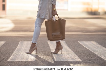 close up of woman legs walking on crosswalk. The woman is wearing shoes on high heels. Handbag in woman hand. - Powered by Shutterstock