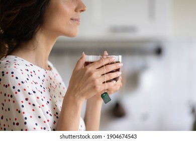 Close Up Of Woman Look In Distance Enjoy Weekend At Home Drinking Warm Tea Dreaming Or Thinking. Happy Dreamy Female Renter Hold Mug Cup With Bag Inside, Have Pleasant Leisure Time Relaxing.