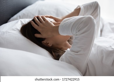 Close up woman lying in bed woke up in early morning touch head with palms feels tired not enough of rest, insomnia sleep disorder anxious by personal problems, unhealthy migraine and headache concept - Shutterstock ID 1727422915