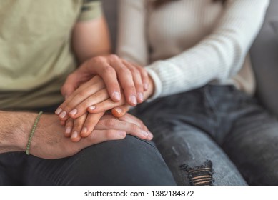 Close up woman and man in love sitting on couch two people holding hands. Symbol sign sincere feelings, compassion, loved one, say sorry. Reliable person, trusted friend, true friendship concept