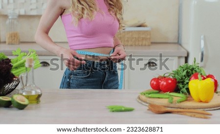 Close up of woman measuring waist near vegetables and fruits on table. Young lady loses weight. Healthy eating.