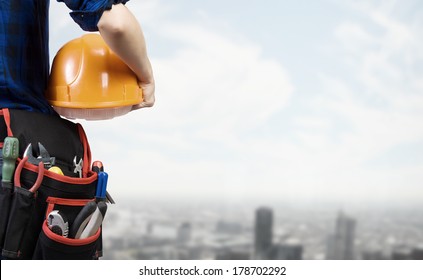 Close up of woman mechanic with yellow helmet in hand against city background - Powered by Shutterstock