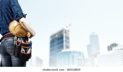 Close Up Of Woman Mechanic With Yellow Helmet In Hand Against City Background