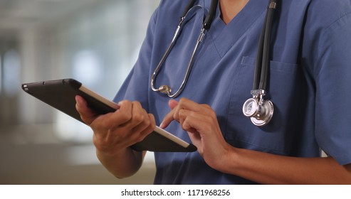 Close up of woman nurse or doctor working on tablet computer inside hospital