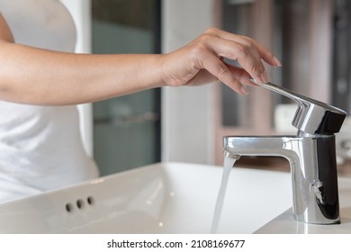 close up Woman open pull chrome faucet washbasin to washing hand soap for corona virus at water tap. push off water running drop off. Bathroom interior background with sink basin faucet tap.