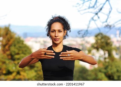 Close Up Woman Outdoors With Earphones And Curly Hair Hands On Chest Sports Outfit