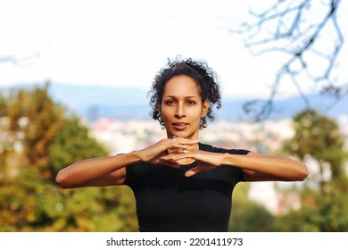 Close Up Woman Outdoors With Earphones And Curly Hair Hands On Chest Sports Outfit