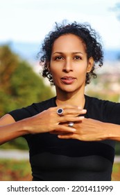 Close Up Woman Outdoors With Earphones And Curly Hair Hands On Chest Sports Outfit