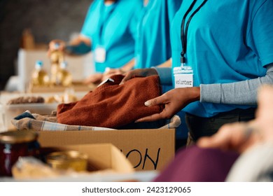 Close up of woman packing clothes into donation boxes volunteering at charitable foundation. - Powered by Shutterstock