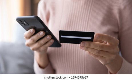 Close up woman paying online by credit card, using smartphone, entering information, young female holding phone, browsing banking service, checking balance, shopping, ordering in internet