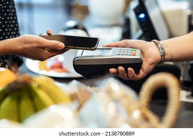 Close up of woman paying for the purchase with her smartphone via NFC in a grocery store. - Powered by Shutterstock