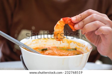 Close up of woman with peel shrimp from tom yum hot and spicy thai food  