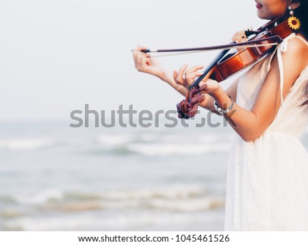 Close up woman playing violin on the beach background.
