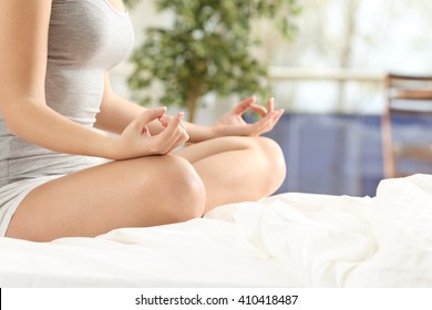 Close up of a woman practicing yoga exercises on the bed at home or hotel with a window with outdoors in the background