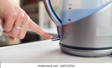 Close Up Of Woman Pressing Power Switch On Electric Kettle To Save Energy At Home