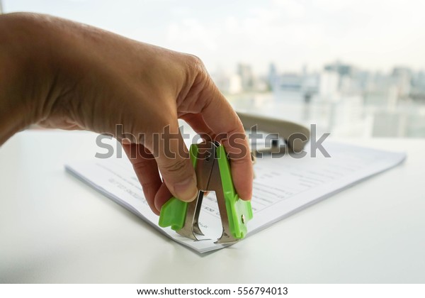 close up woman pull staple from business\
documents by staple\
remover