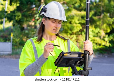 Close up of woman in reflective clothing using GPS land surveying tool with screen