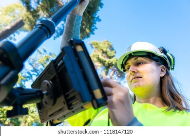Close up of woman in reflective clothing using GPS land surveying tool with screen