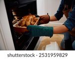 Close up of woman roasting turkey in the oven.