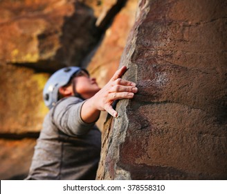 A Close Up Of A Woman Rock Climbing On A Sheer Cliff Outdoor With A Blue Helmet On For Safety 