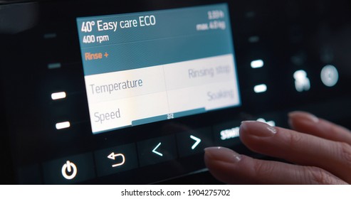 Close Up Of Woman Selecting Regime And Temperature On Washing Machine Control Panel. Cropped Shot Of Hand Pushing Sensor Buttons On Display Of Modern Washing Machine