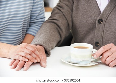 Close Up Of Woman Sharing Cup Of Tea With Elderly Parent