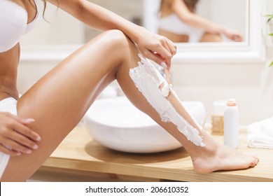 Close up of woman shaving legs in bathroom