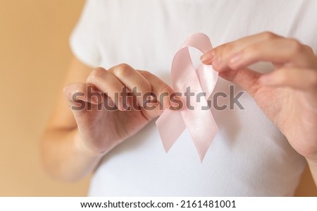 Close up of woman showing pink ribbon symbolizing breast cancer.