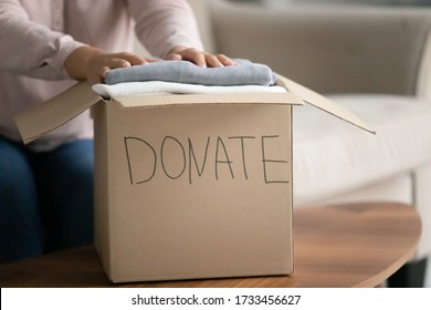 Close up woman sit on sofa near big cardboard box full of new clothes, old stuff used apparels is prepared for donation. Help for poor needy people, humanitarian aid, charity and benevolence concept - Shutterstock ID 1733456627