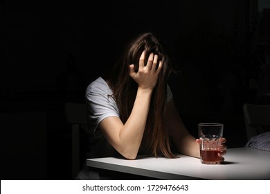 Close up of woman sitting and holds glass with whiskey or cognac having alcohol addiction, depressed female drinking strong alcohol suffering from personal relationships problems