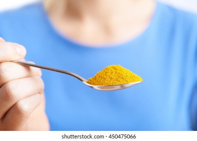 Close Up Of Woman With Spoonful Of Tumeric Powder