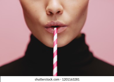 Close up of woman with straw in pink background. Face of female model with a straw.