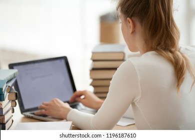 Close Up Woman Student Sitting At The Desk Typing Writing Message Mail Looking At Computer With Mock Up Blank Screen, View Over The Shoulder. Girl With Heaps Stack Of Books Studying At Home Or Library