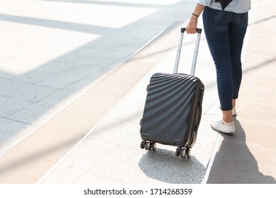 Close up woman and suitcase trolley luggage in airport. People and lifestyles concept. Travel and Business trip theme. Woman wear jeans going on tour and traveling around the world by alone solo girl